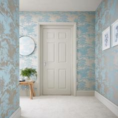 an empty room with blue and white wallpaper, a plant on the floor and a mirror