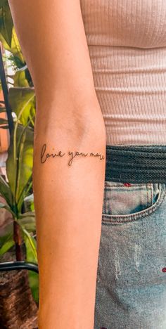 a woman with a tattoo on her arm that says, love you mom in cursive writing