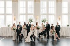 a large group of people posing for a photo in front of some windows and tables