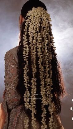 the back of a woman's head with long curly hair and flowers on it