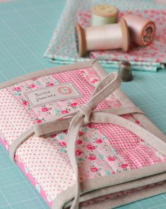 three pieces of fabric are sitting on a table with thread and spools in the background