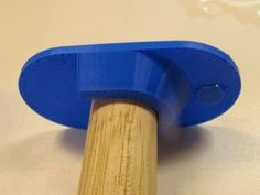 a close up of a blue object on a white surface with a wooden stick in the foreground