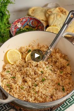 a pan filled with rice and lemons on top of a table next to other food