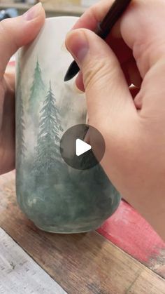 someone is painting a mug with trees on it