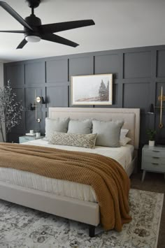 a bedroom with a bed, ceiling fan and pictures on the wall above it that has been painted dark gray