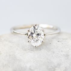 a white diamond ring sitting on top of a rock