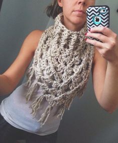 a woman taking a selfie in front of a mirror wearing a scarf and holding a cell phone