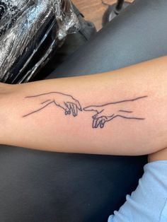 two hands touching each other with one hand holding the other's finger tattoo on arm