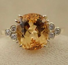 "This beautiful engagement ring is made in 14k yellow gold. The natural imperial topaz weight is 4.35 carats. The 6 bezel set side diamonds are VS clarity and G color range .18 carats total weight . Total gem weight 4.53 carats. We can make it any size from 5-7 and you still be able to return it within the listed time frame. Sizing outside of that range requires a resize fee if for any reason the ring is retuned. Ring sizing may add additional handling time. We love this ring because it represen Imperial Topaz Engagement Ring, Yellow Topaz Ring, Topaz Wedding Ring, Engagement Ring Cushion, Huge Rings, Ring Cushion, Engagement Rings Cushion, Citrine Jewelry, Imperial Topaz