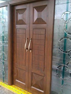 two wooden doors sitting next to each other in front of a wall with glass panels