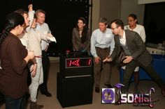 a group of people standing around a table with a clock on it's side