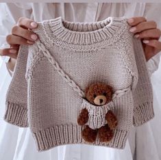 a person holding up a sweater with a teddy bear on it