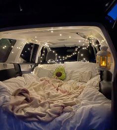 the interior of a vehicle with lights and blankets on it's bed in the back