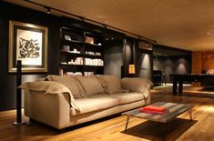 a living room filled with furniture next to a table and bookshelf on the wall