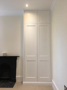 an empty room with a fireplace and white closets on the wall, next to a black fire place