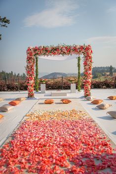 an outdoor ceremony setup with petals on the ground and flowers in the aisle for decoration