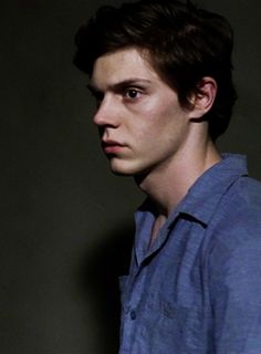 a young man in a blue shirt looking at the camera