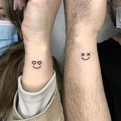 two people with matching tattoos on their wrists wearing face masks and holding each other's hands