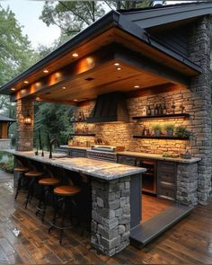 an outdoor kitchen with stone counter tops and built in grilling area, surrounded by wood flooring