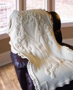 a white blanket sitting on top of a leather chair