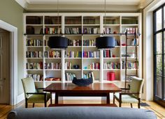 a dining room table and chairs with bookshelves in the background