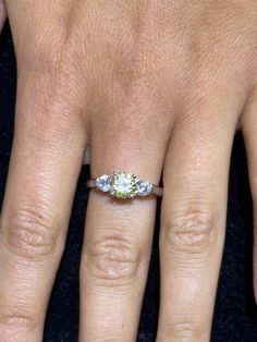 a close up of a person's hand with an engagement ring on their finger