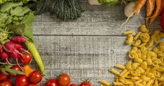 several different types of vegetables and pasta on a wooden table