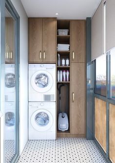 a washer and dryer in a small room with wooden cupboards on the wall