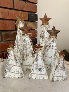 three wooden christmas trees with brown stars on top, tied in twine and sitting next to a brick wall