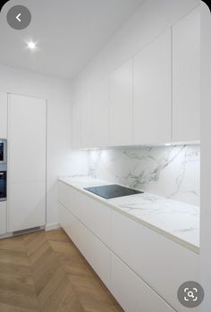 a kitchen with white cabinets and marble counter tops, along with an oven in the corner