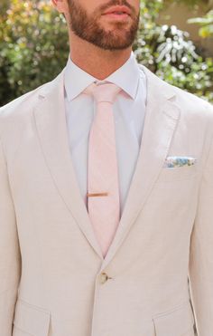 a man wearing a white suit and pink tie