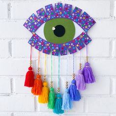 an eye with tassels hanging from it's side on a brick wall