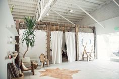 a room with white curtains and wooden furniture in the center, along with a cow skin rug on the floor