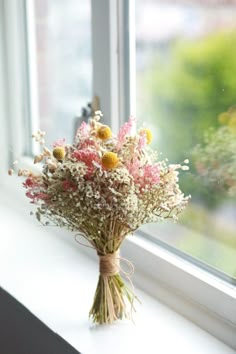 a bouquet of flowers sitting on top of a window sill next to a window