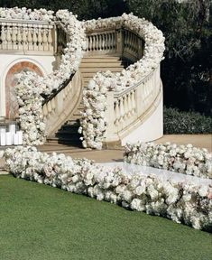 an outdoor wedding setup with white flowers and greenery on the stairs, surrounded by lush green grass