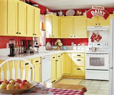 a kitchen with yellow cabinets and red walls, white appliances and checkered table cloth