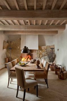 a dining room table with chairs and a fire place in the center, surrounded by stone walls