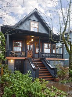 a house with stairs leading up to the front door and second story on top of it