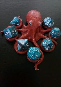 an octopus with blue and red dices on it's back, sitting on a black surface