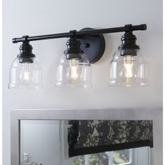 three light bathroom vanity fixture with clear glass shades and black metal finish on the mirror