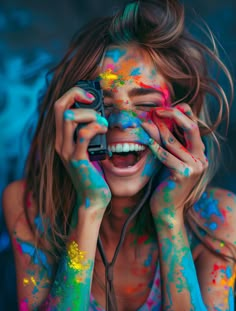 a woman covered in colorful powder holding a camera