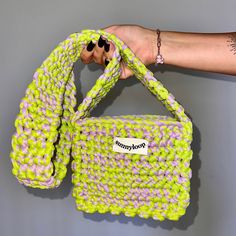 a hand holding a green and purple bag