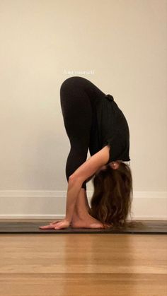 a woman in black shirt and leggings doing a handstand on the floor