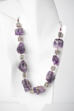 Shock and amaze everyone you know with this bold, beautiful necklace. It is made of amethyst rough cut stones with silver cubes and Swarovski© crystal. The silver adjustable length chain allows you to wear the necklace in a variety of styles. Amethyst is the perfect piece to wear with your favorite work clothes or your fancier attire. Silver Amethyst Necklace With Raw Stone, Silver Amethyst Crystal Necklaces, Silver Amethyst Crystal Necklace With Stones, Amethyst Rock, Fancy Attire, Rock Necklace, Murano Glass Beads, Amethyst Beads, Work Clothes