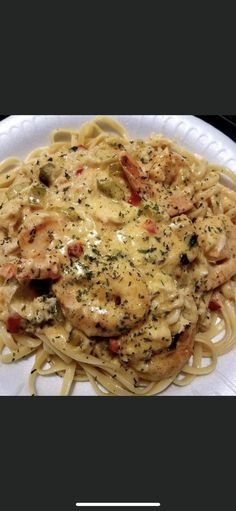 a white plate topped with pasta covered in sauce and shrimp on top of it's own