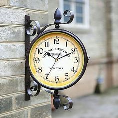 a clock mounted to the side of a brick wall next to a building with windows