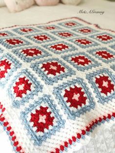 a red, white and blue crocheted blanket sitting on top of a bed