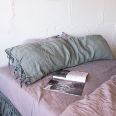 a bed with a book and pillow on top of it next to a wall mounted clock