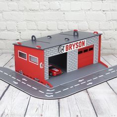 a toy car is parked in a garage on the road next to a white brick wall