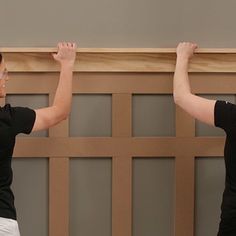 two women in black shirts and white pants are holding their hands up to the ceiling